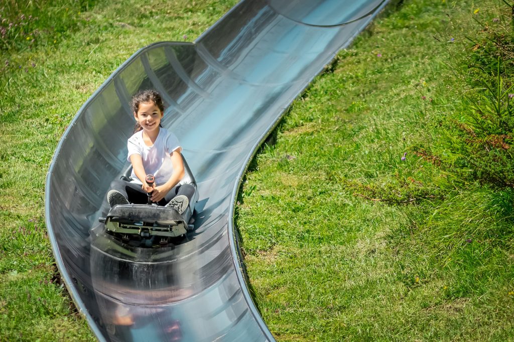 Young Girl Having Fun Riding Summer Toboggan (sled) Down A Hill
